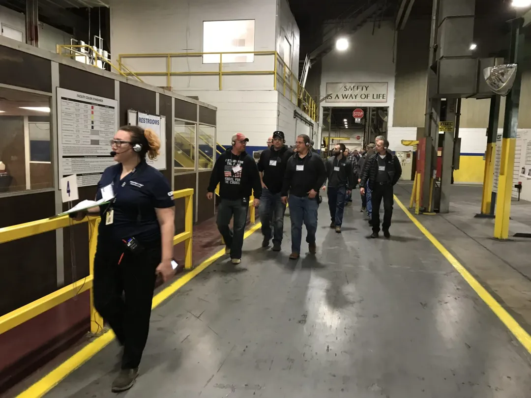 Guide leading a group wearing headsets through a factory