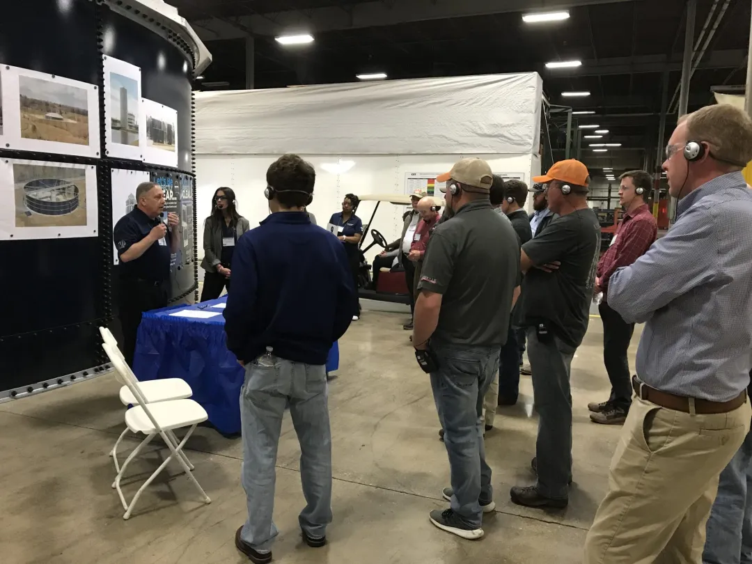 Group wearing headsets listening to a presenter at an event booth