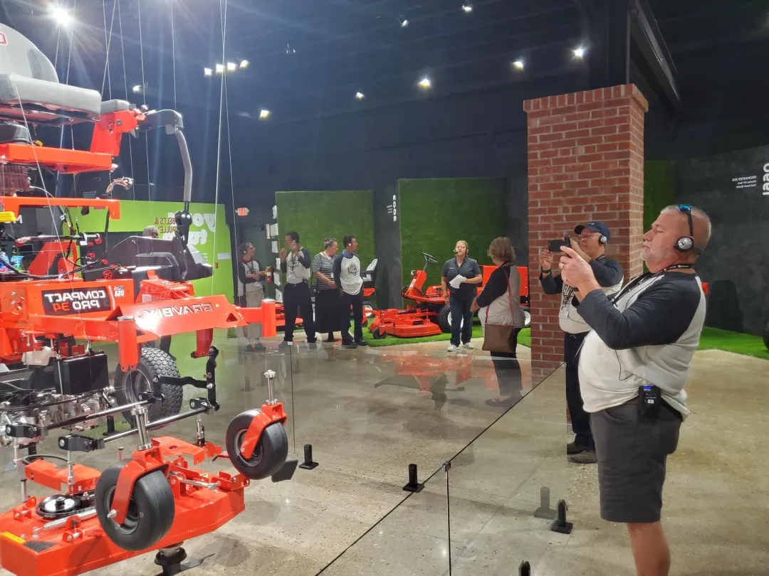 A guide with a headset leads a tour group through an equipment showroom