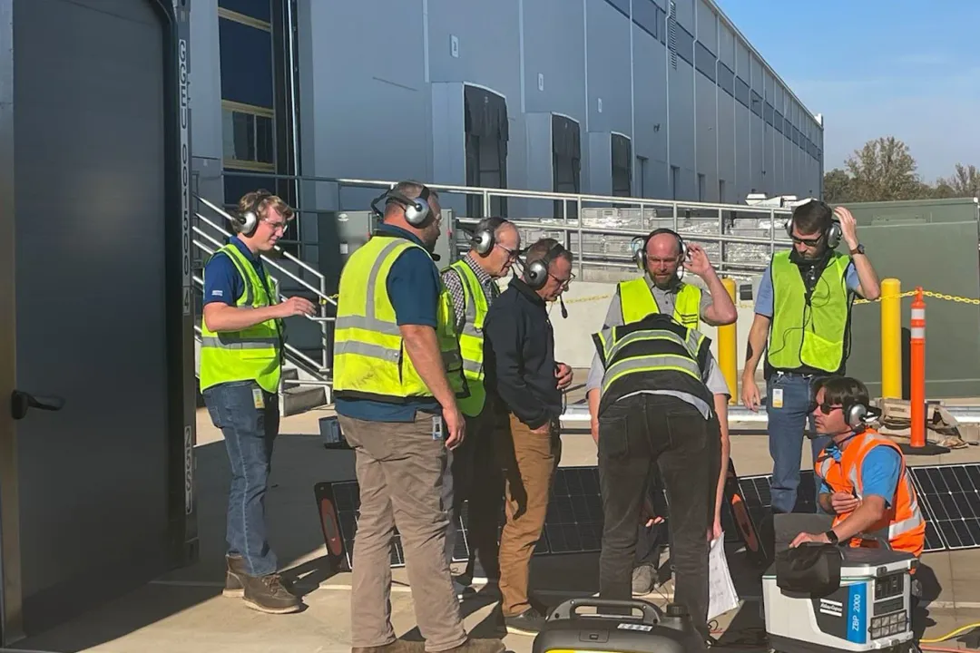 Tour group in safety vests wearing Plant-Tours.com headsets outside a facility