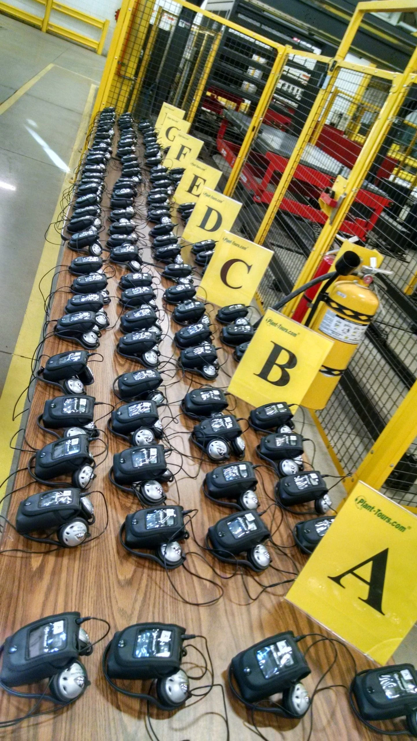 Rows of tour receivers and headsets laid out on a floor in lettered groups A, B, C and D