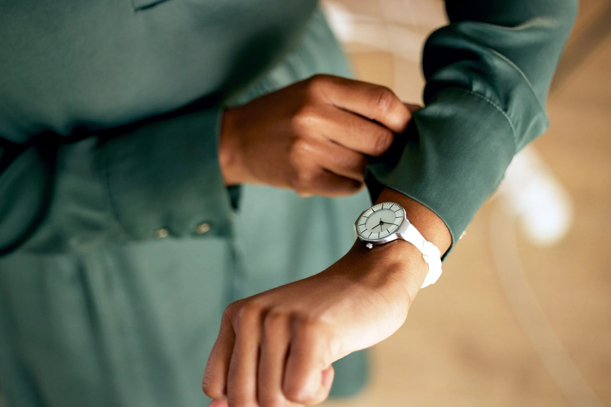 Person in a green shirt checking the time on a wristwatch