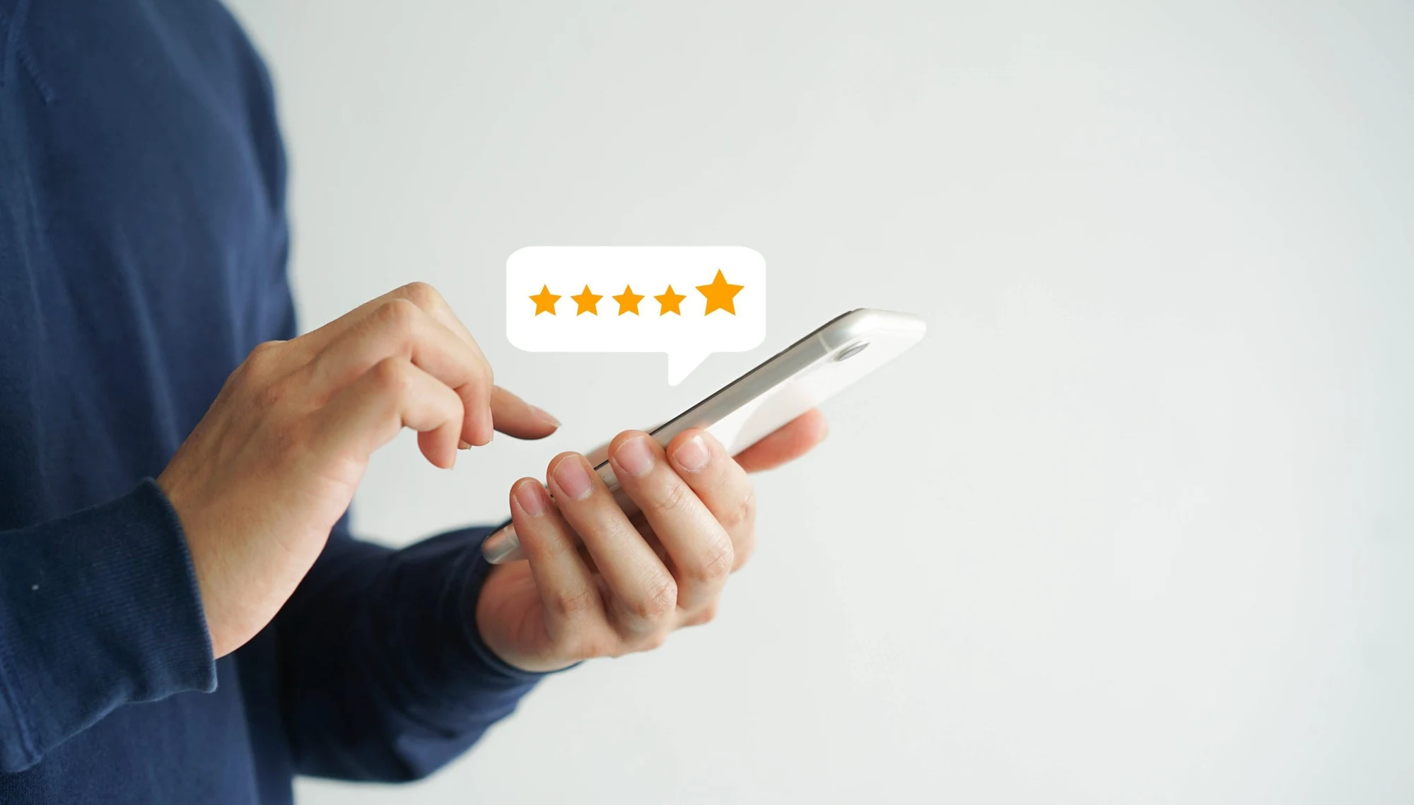 Hand holding a smartphone with a five-star rating speech bubble above the screen