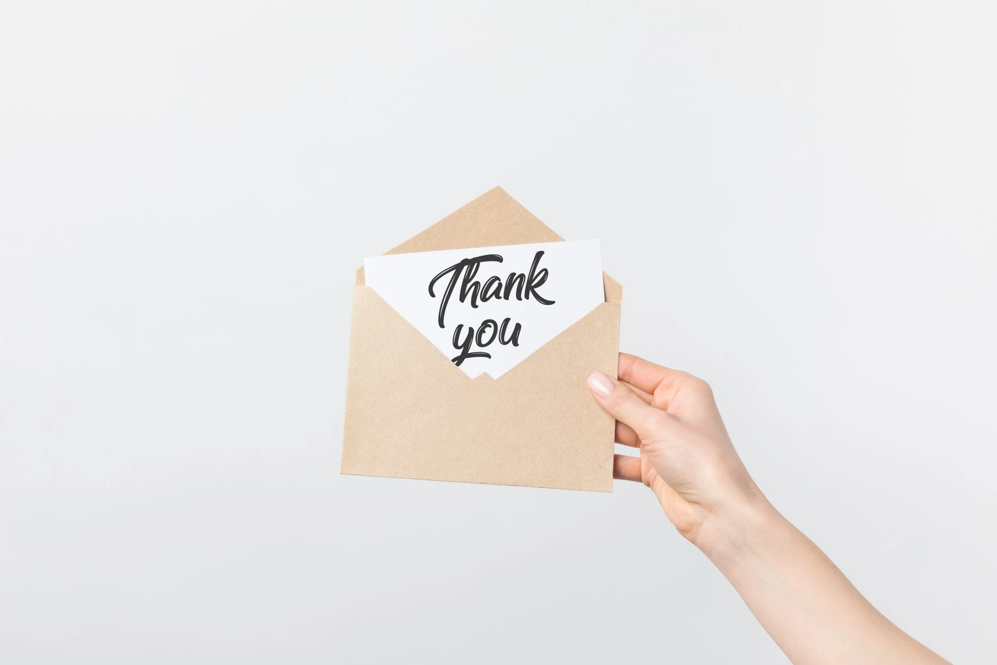 Hand holding a kraft envelope with a card reading Thank you