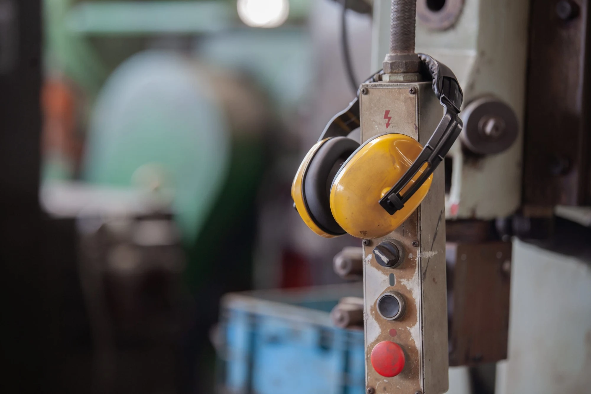 Yellow ear muffs hanging on a control pendant of an industrial machine