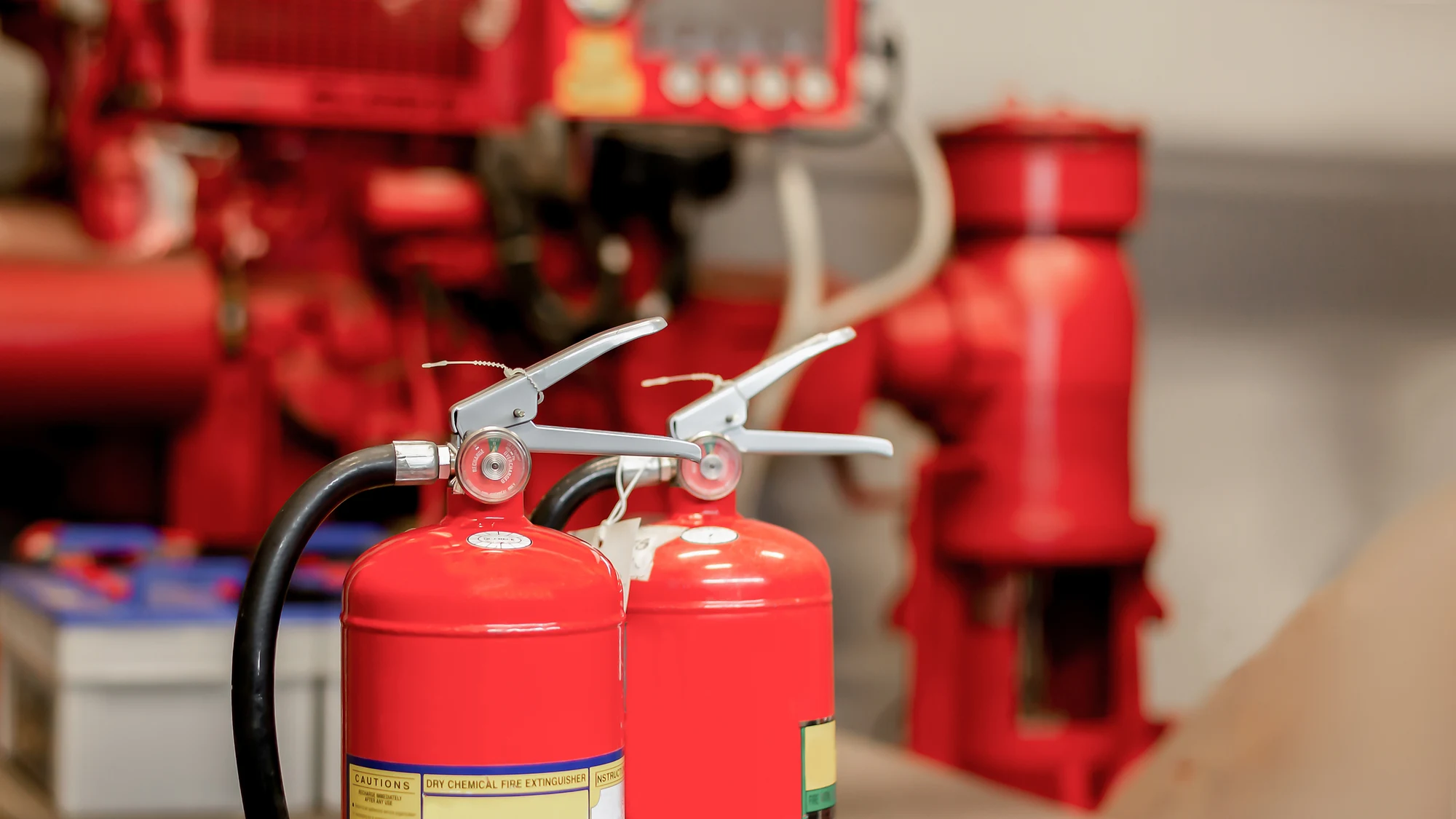 Red fire extinguishers in front of red fire suppression pipework