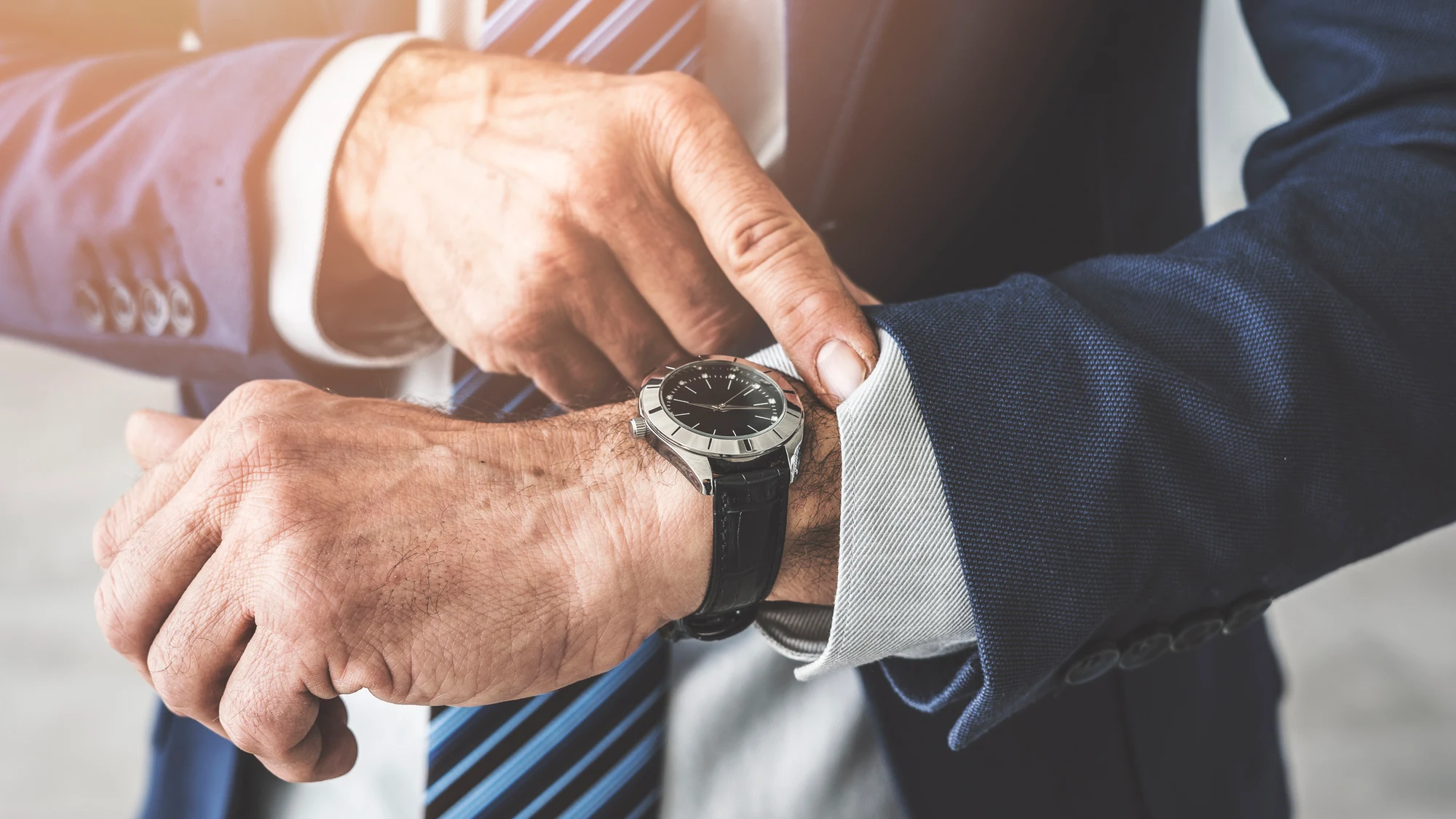 Man in a suit checking the time on his wristwatch