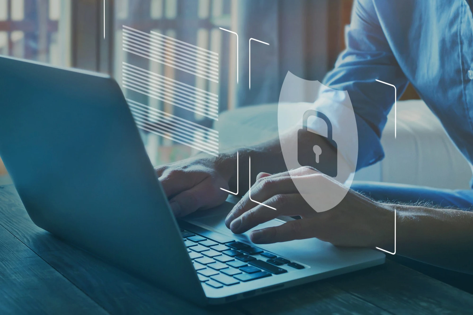 Hands typing on a laptop with a shield and padlock security icon overlaid