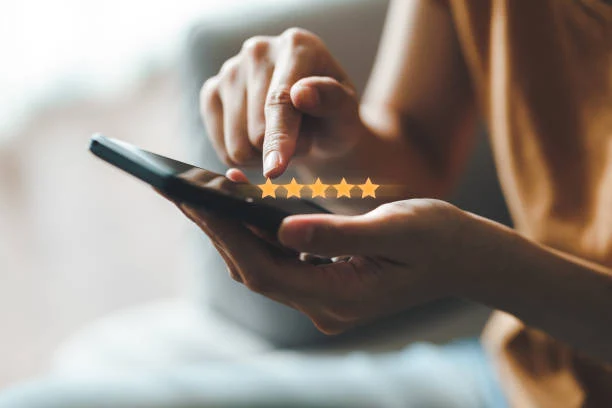 Hand tapping a five-star rating on a smartphone screen