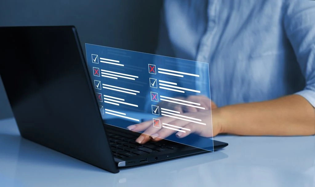Person using a laptop with a digital checklist displayed above the keyboard