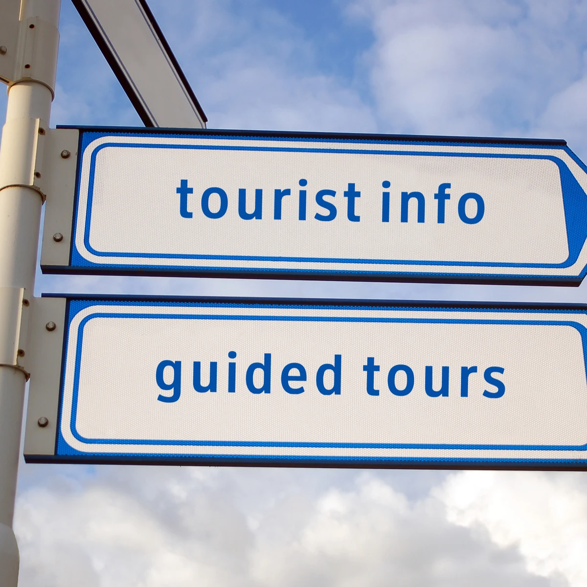 Street signs reading tourist info and guided tours against a cloudy sky